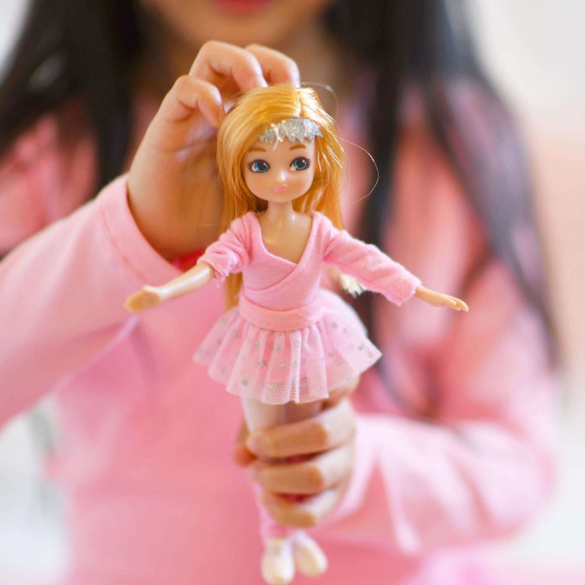 A child holding a Lottie doll dressed for ballet class