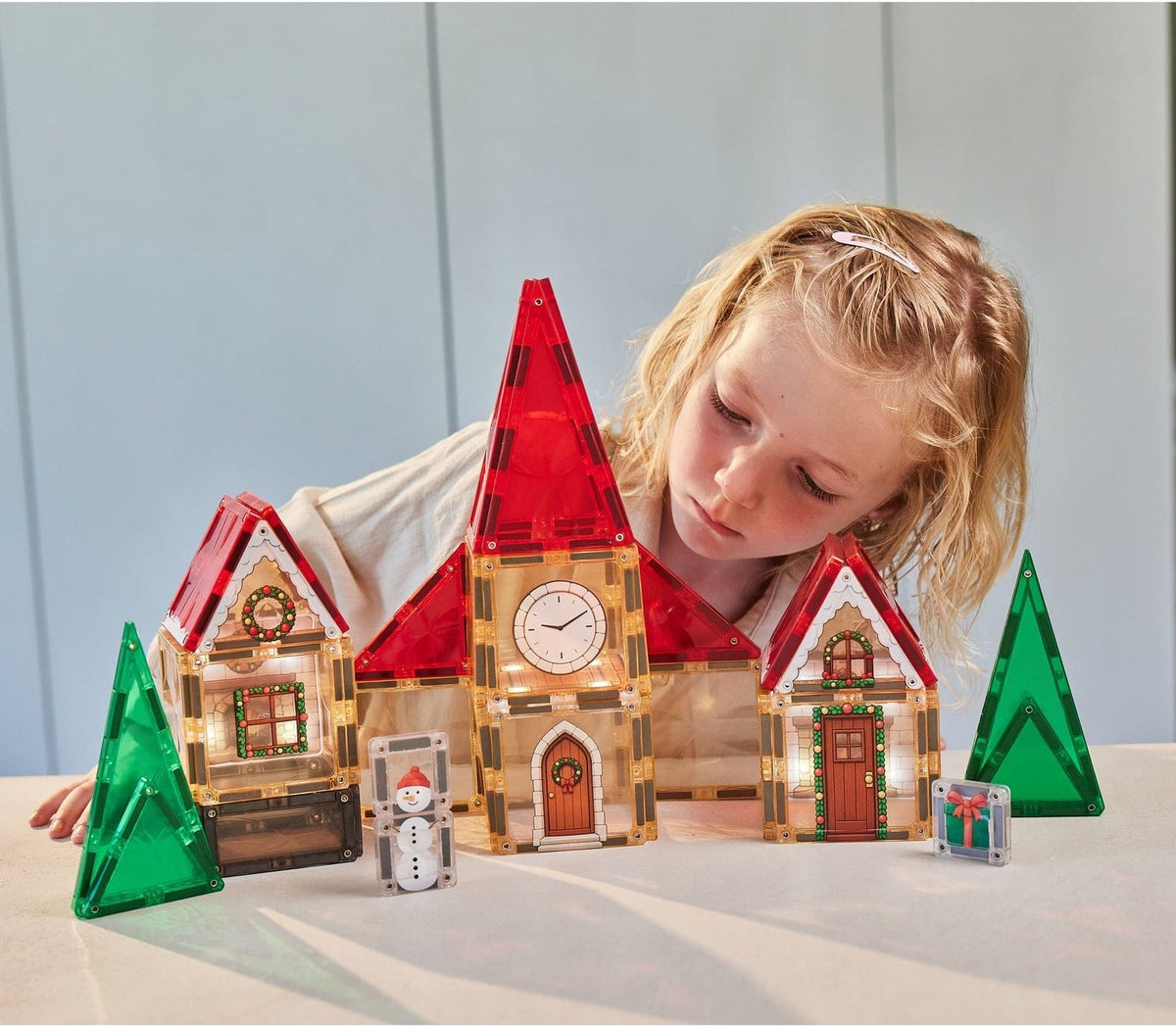 Child building a magnetic tile Christmas village