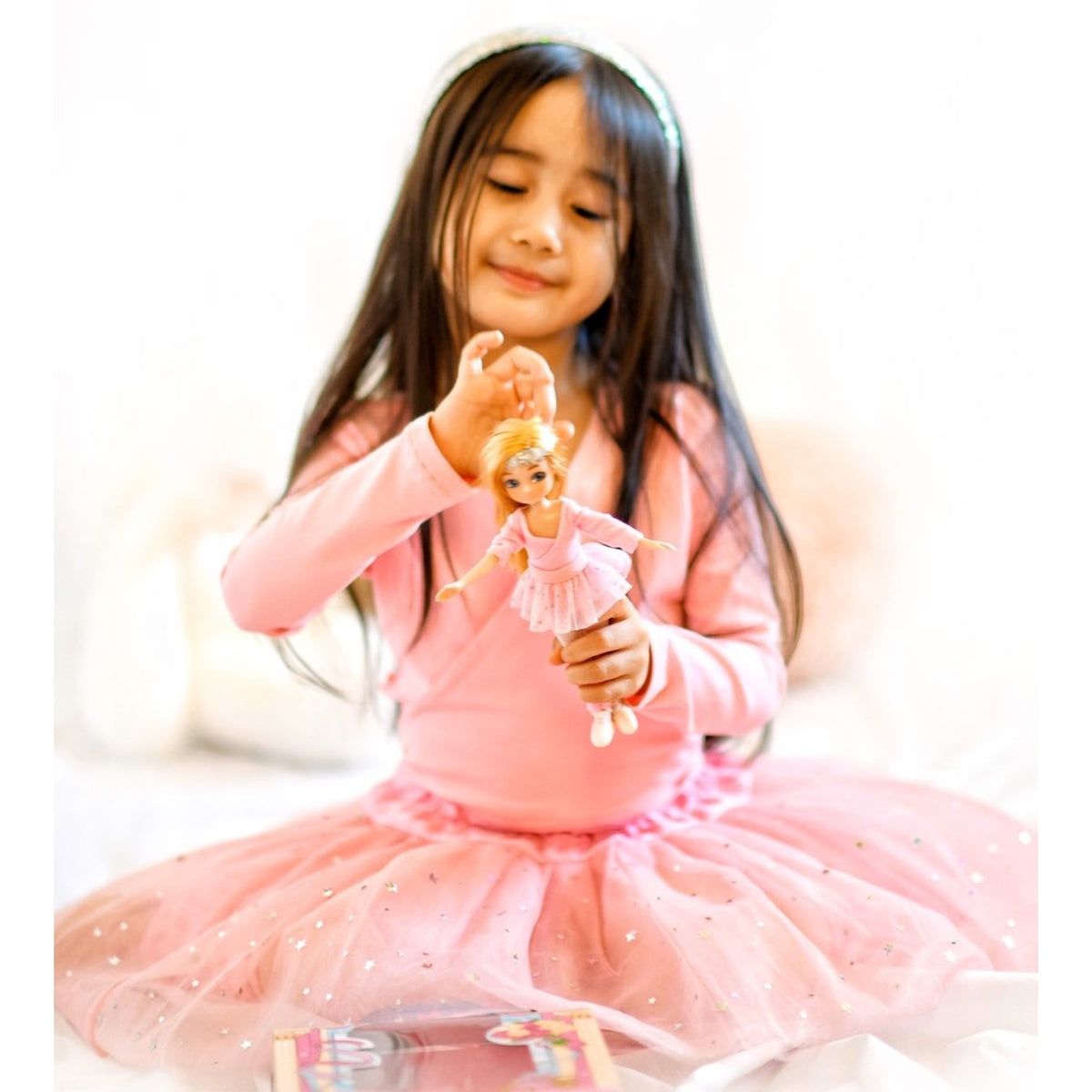 A girl in a pink tutu with her Ballet Class Lottie doll