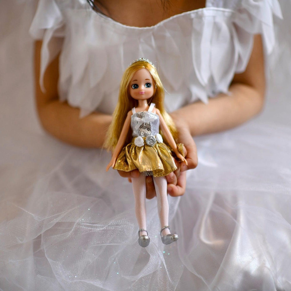 A girl in a white swan dress holding her Swan Lake Lottie doll