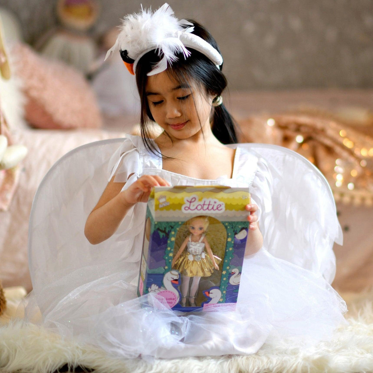A girl in a swan costume with her Swan Lake Lottie doll in its gift box