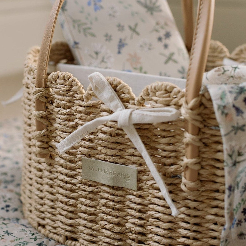 Scallop edge nappy caddy basket with a muslin on a nursery rug
