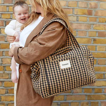 Smiling baby with a Finnson Sanna gingham changing bag