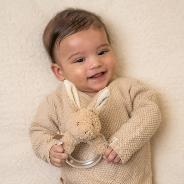 Smiling baby holding a Little Dutch Baby Bunny ring rattle