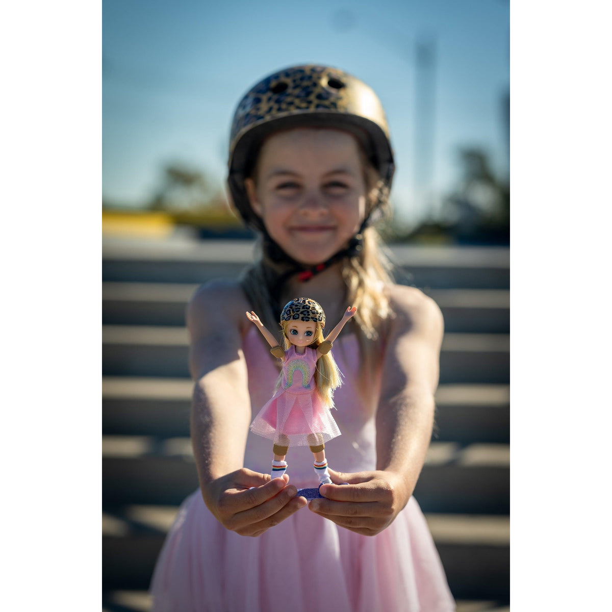 A girl in a skate helmet holding her Skate Park Lottie doll
