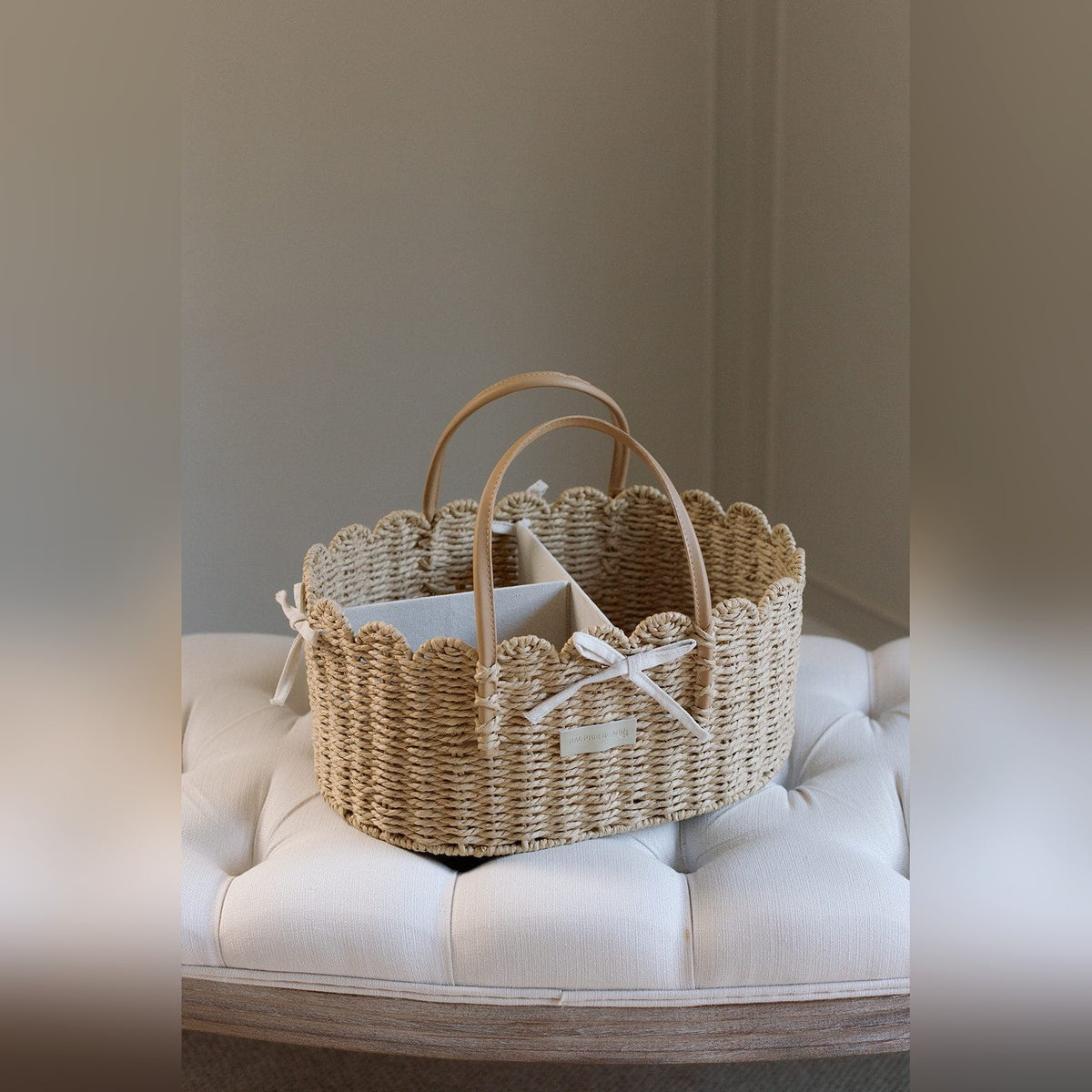 Woven scallop edge nappy caddy basket on a tufted nursery footstool